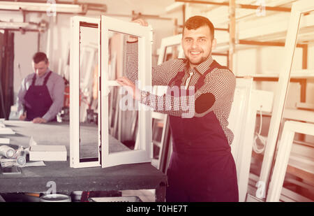 Workman is demonstrating the window frame in workshop. Stock Photo