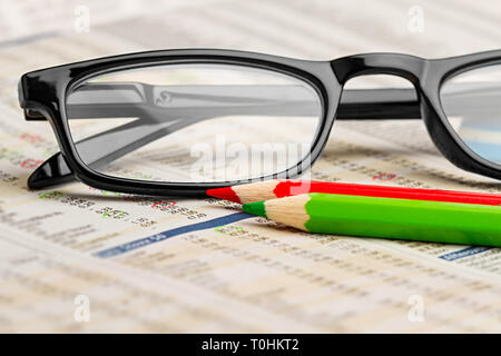 glasses red green pen pencil on newspaper with stock market exchange data chart finance business concept cash background Stock Photo