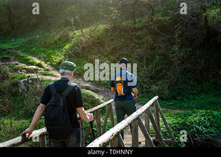 Hikers crossing the wooden bridge over small river Stock Photo