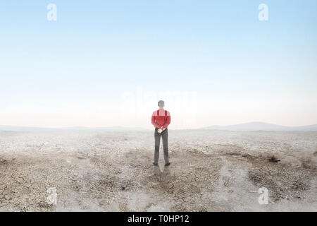 Rear view of asian businessman standing on the dry land over blue sky background. Earth day concept Stock Photo