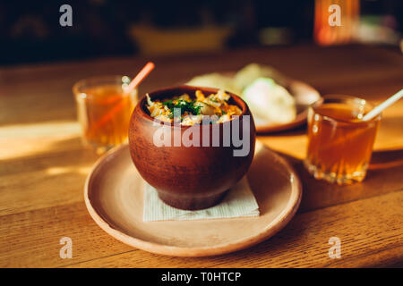 Delicious dumplings with chicken and dill in clay pot and drinks served in cafe. Ukrainian traditional food. National cuisine Stock Photo