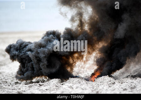Explosion on the beach, billowing black smoke. Stock Photo