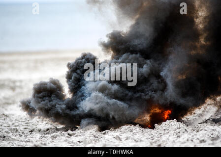 Explosion on the beach, billowing black smoke. Stock Photo