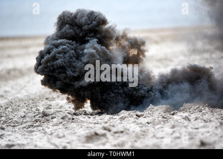Explosion on the beach, billowing black smoke. Stock Photo