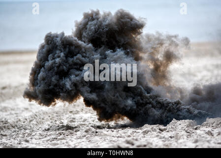 Explosion on the beach, billowing black smoke. Stock Photo
