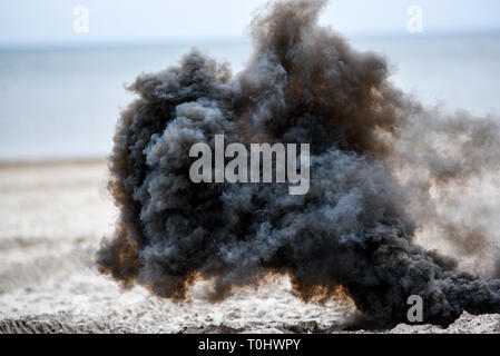 Explosion on the beach, billowing black smoke. Stock Photo