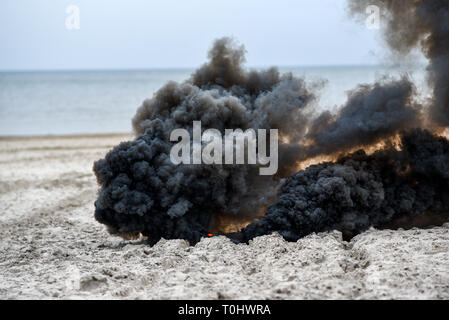 Explosion on the beach, billowing black smoke. Stock Photo