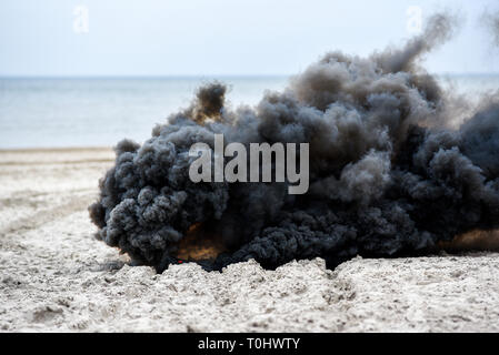 Explosion on the beach, billowing black smoke. Stock Photo