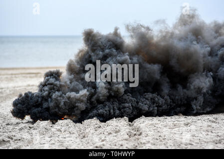 Explosion on the beach, billowing black smoke. Stock Photo
