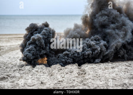 Explosion on the beach, billowing black smoke. Stock Photo