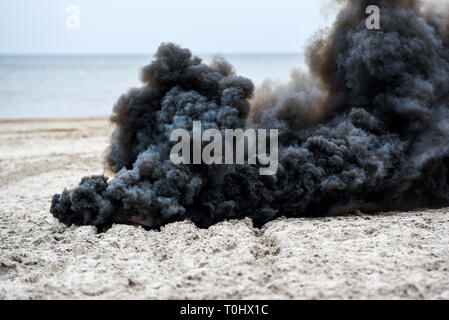 Explosion on the beach, billowing black smoke. Stock Photo