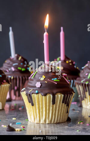 Birthday cupcakes with candles. Vanilla cupcakes with a meringue frosting and dark chocolate shell Stock Photo