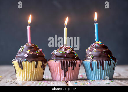 Birthday cupcakes with candles. Vanilla cupcakes with a meringue frosting and dark chocolate shell Stock Photo