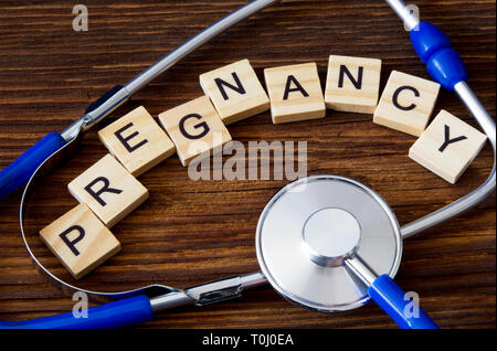 'Pregnancy' word written on wooden blocks between sthethoscope Stock Photo