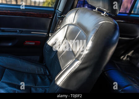 Leather car seat illuminated by the sun, inside the used car, visible signs of use. Stock Photo