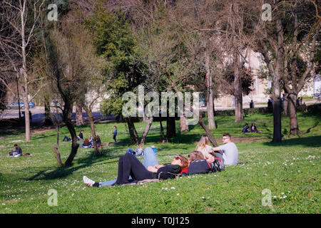 Rome, Italy - 3 March 2019: In the public park of Villa Borghese, some boys lie on the grass in a moment of relaxation. A boy and a girl sunbathe. On  Stock Photo