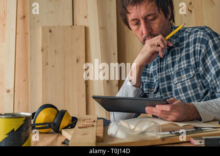 Carpenter using digital tablet in small business woodwork workshop for planning a new DIY project Stock Photo