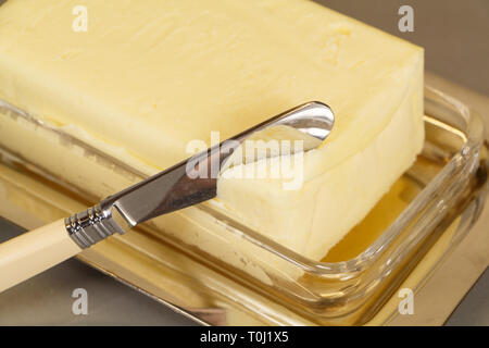 Knife and pack of butter in a butter dish made of metal and glass Stock Photo