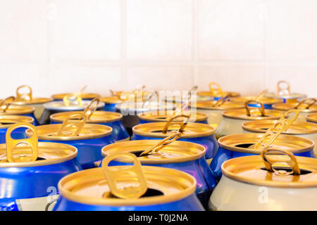 'Wide-mouth' blue and orange drink cans on a tiled background, with the stay-on-tabs opened. Made from aluminium, these containers can hold carbonated Stock Photo