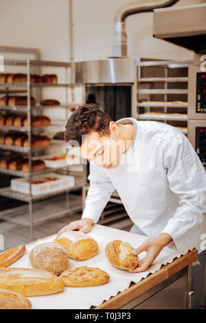 Baker looking at the tray and checking the readiness of bread Stock Photo