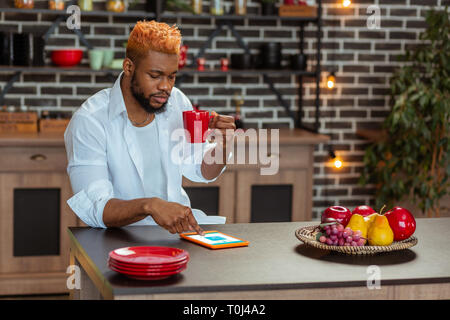 Nice thoughtful young man using his tablet Stock Photo