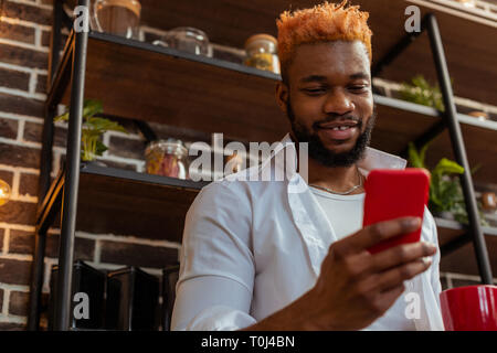 Positive African American man holding his smartphone Stock Photo