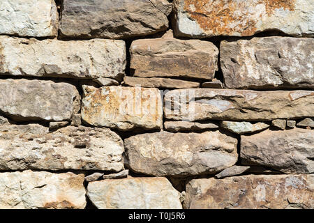Close up of old flat brown and gray stone wall texture. Layered rocks on a house or building. Architectural stone wall exterior typical in Bulgaria Stock Photo