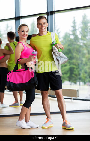 sportive couple with water bottles and bags in gym Stock Photo