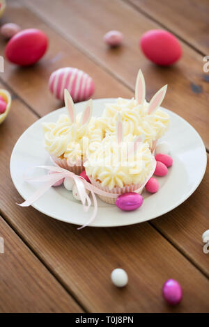 cupcakes with easter eggs and candies on table Stock Photo