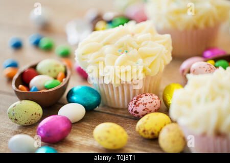 cupcakes with chocolate eggs and candies on table Stock Photo