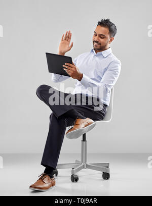 indian businessman with tablet pc on office chair Stock Photo