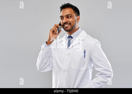 smiling indian male doctor calling on smartphone Stock Photo