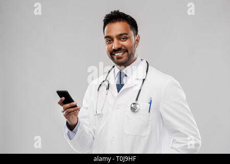 smiling indian male doctor with smartphone Stock Photo