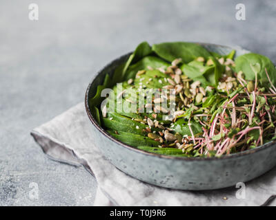 Green healthy salad of spinach, sprouts, avocados and various seeds in a blue bowl Stock Photo