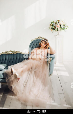 Elegant future mother posing in long powder dress. Stock Photo