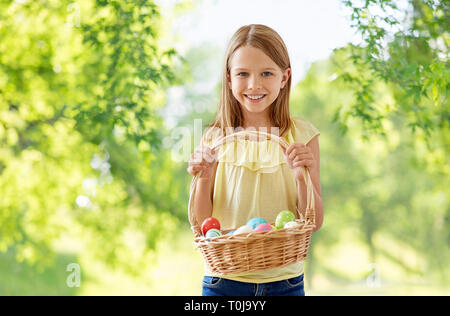 happy girl with colored eggs in wicker basket Stock Photo