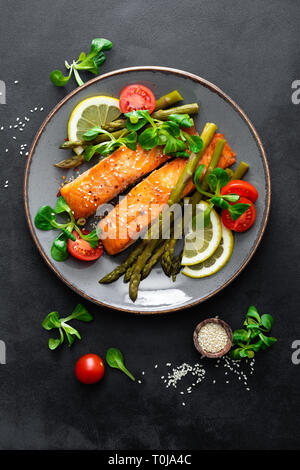 Grilled salmon fish steak, asparagus, tomato and corn salad on plate. Healthy dish for lunch. Top view Stock Photo