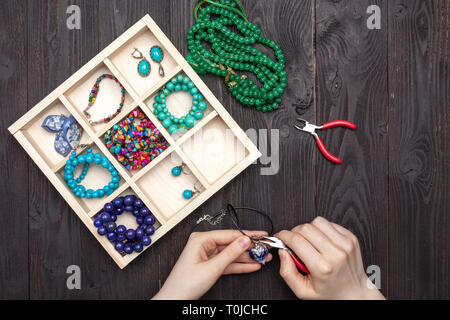 Handwork at home, the girl makes jewelry hands on the table Stock Photo