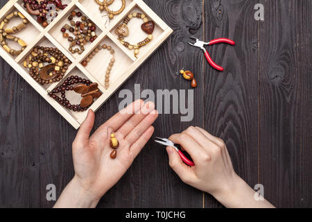 Handwork at home, the girl makes jewelry hands on the table Stock Photo