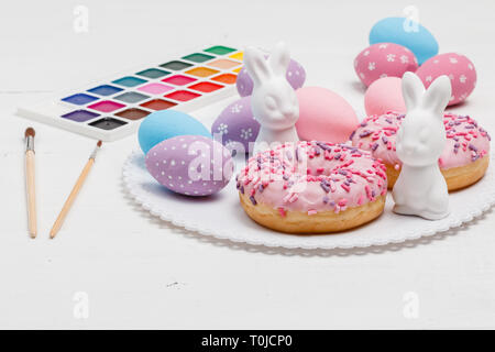 Easter bunnies and eggs on the table with donuts Stock Photo