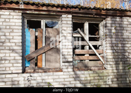 two boarded windows of an abandoned house outdoor closeup on sunny day Stock Photo