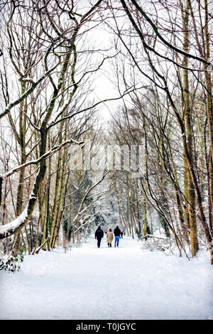 Winter scene of people strolling in the snow on Parkland Walk, a disused railway line in North London, suitable for a Christmas or greetings card Stock Photo