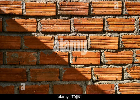 Sunlight falls on colorful brick wall and creates deep shadow Stock Photo