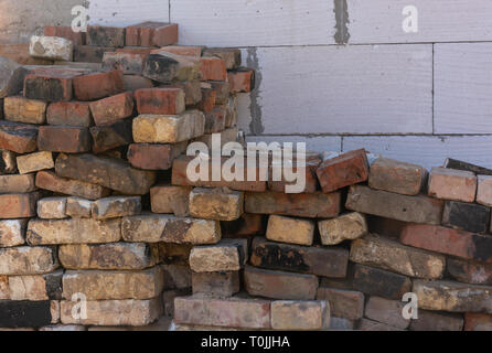 red bricks piled against a white wall Stock Photo