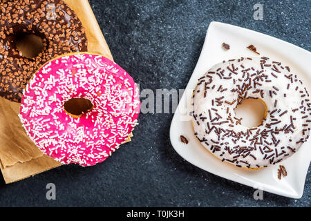 Chocolate, red, and white donuts on black stone table Stock Photo