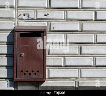 old mail box hanging on the white brick wall day Stock Photo