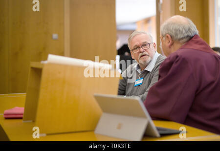 21 March 2019, Baden-Wuerttemberg, Karlsruhe: The father of a plaintiff (l) represents his son in a courtroom of the Federal Court of Justice (BGH) and speaks with his lawyer Siegfried Mennemeyer (r). The BGH negotiates there on the liability of teachers in emergencies in sports instruction. The then 18-year-old plaintiff had become unconscious while warming up in sports class and suffered brain damage, which made him 100 percent severely handicapped - he now wants several hundred thousand euros in compensation for pain and suffering from the state of Hesse. Photo: Christoph Schmidt/dpa Stock Photo