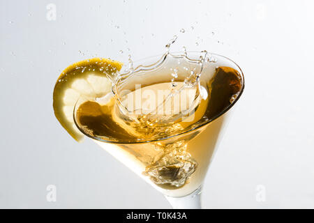 Close up of an olive splashing on a glass of martini with a slice of lemon Stock Photo