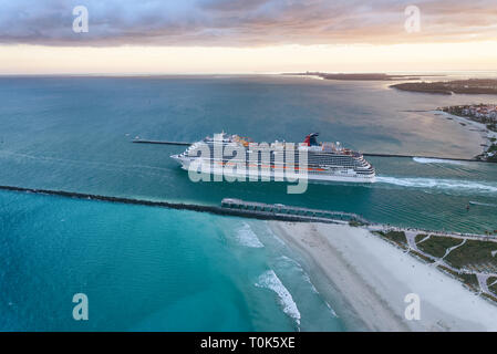 Cruise ship leaving Miami Port at dusk. Amazing aerial view from helicopter on a cloudy sunset. Stock Photo