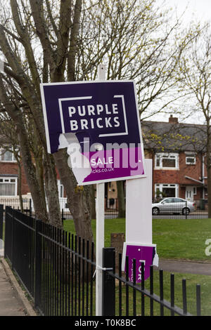 Ripped and broken Purple bricks estate agents for sale or sold sign Stock Photo